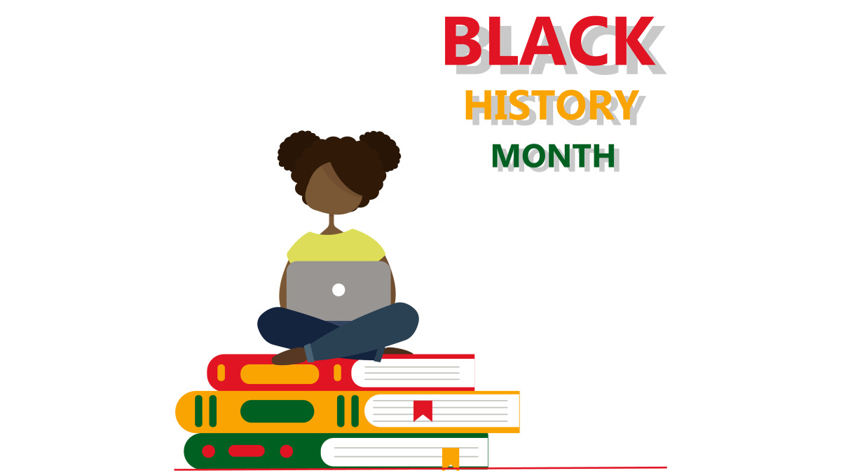 Student working on a computer while sitting on books with title "Black History Month"