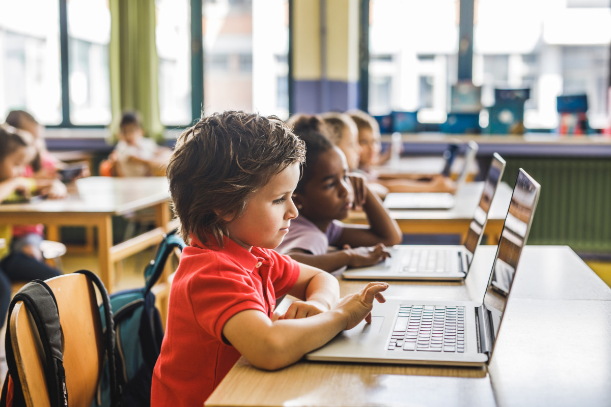 A class of young students works on their laptops