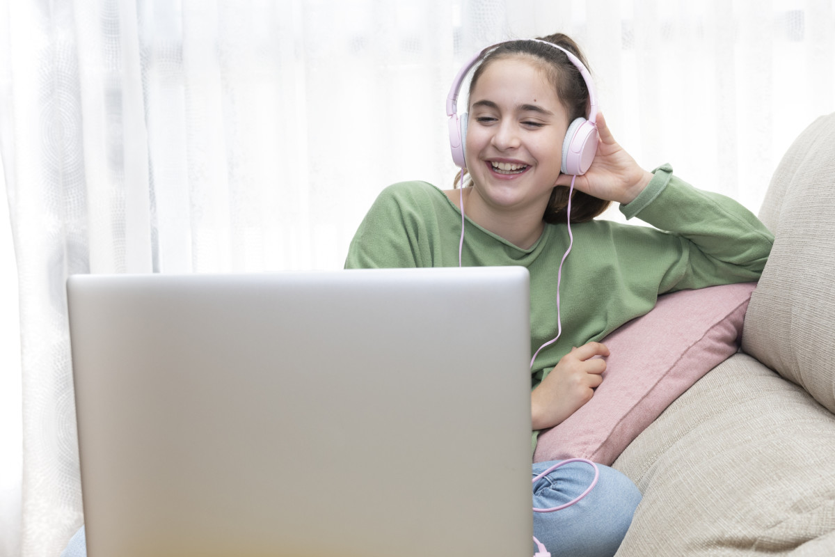 Girl wearing headphones and smiling at computer