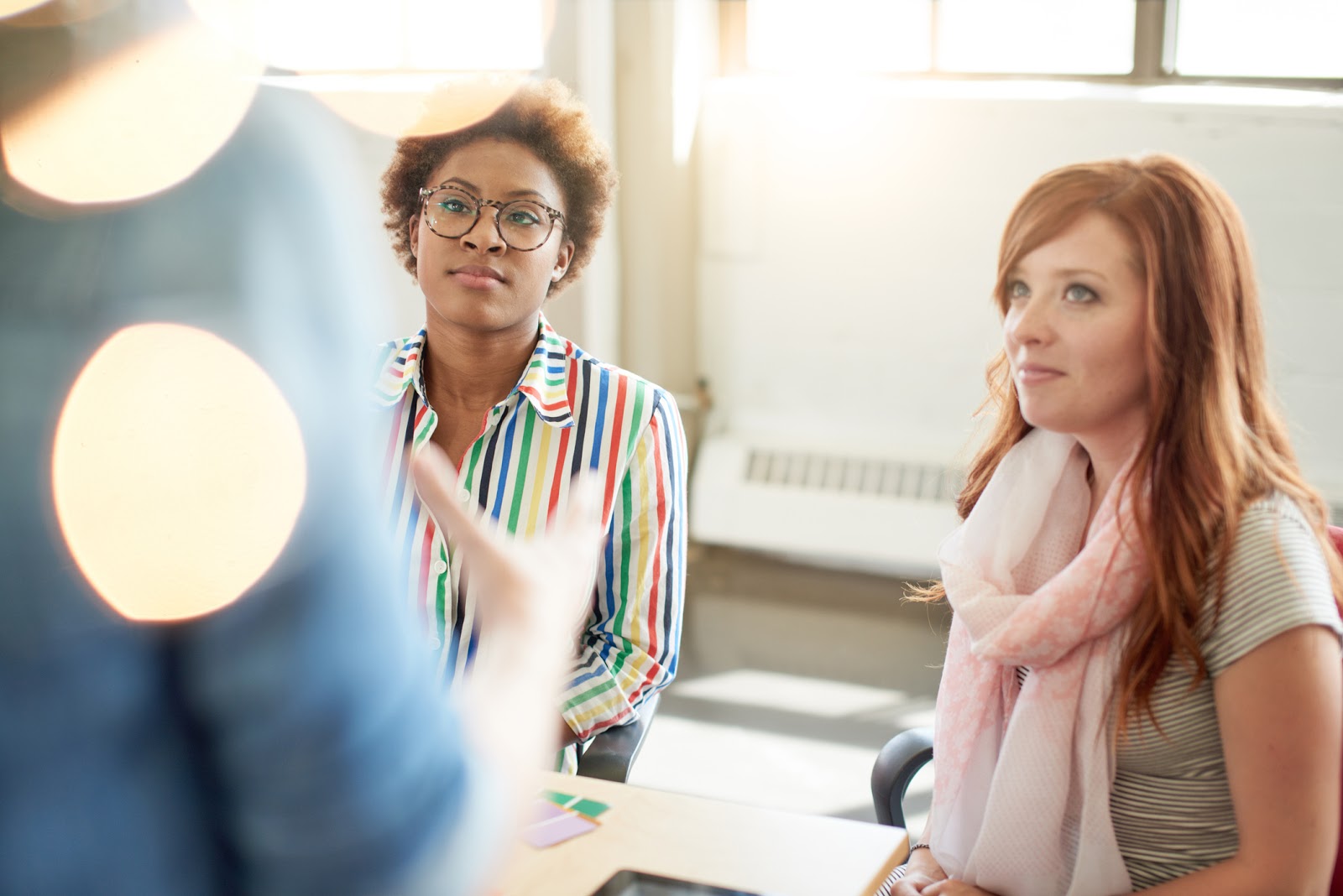 An image of two teachers listening to an instructor at the front of a classroom