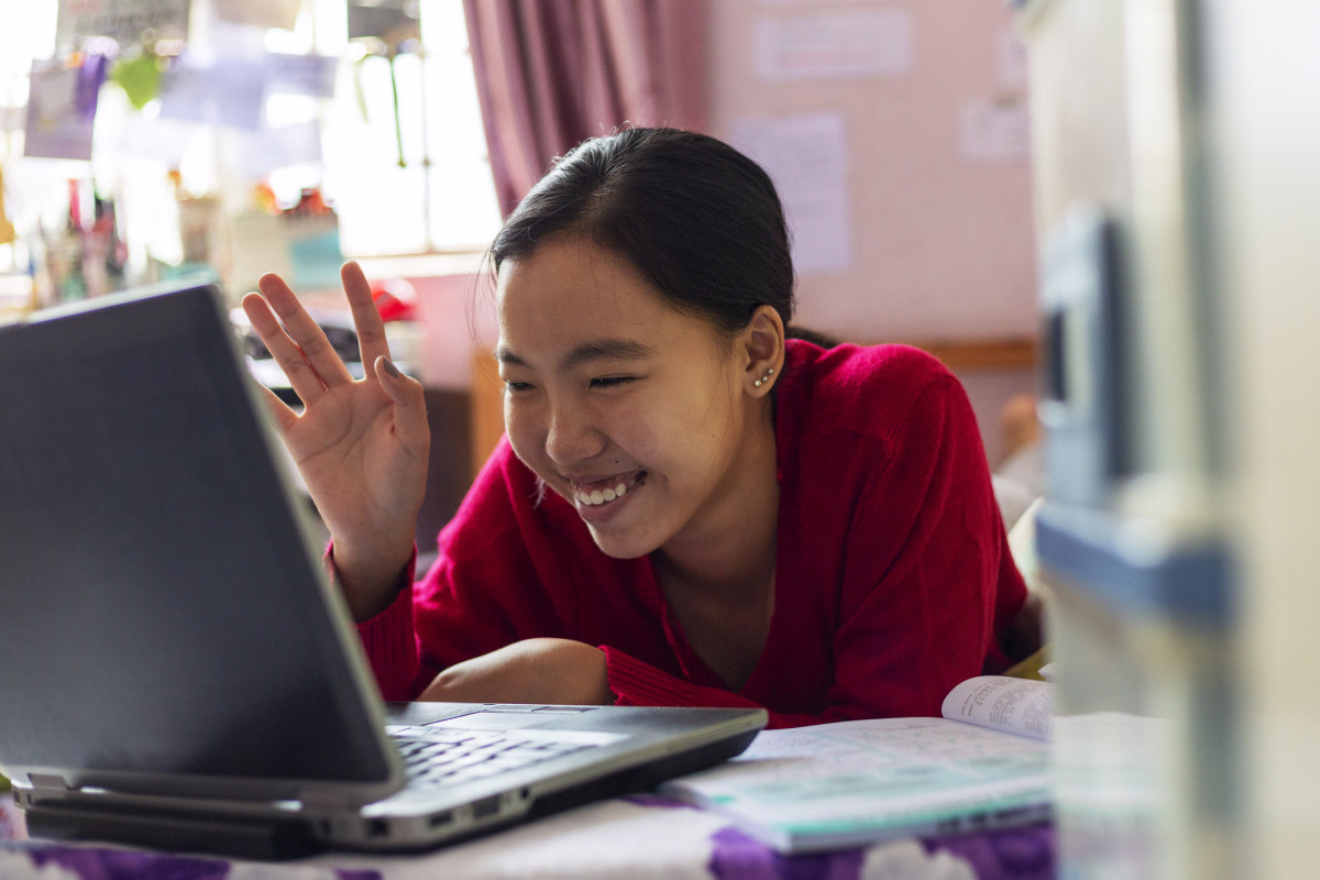 Student smiling at her computer while Learning at home