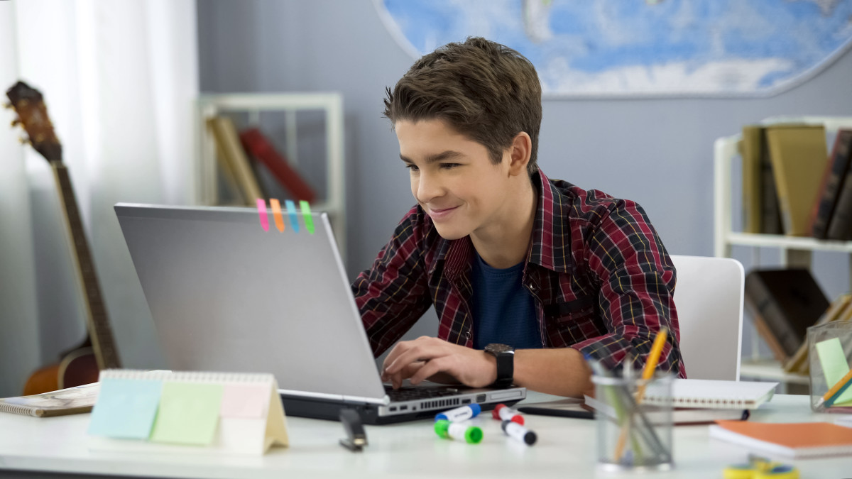 Student smiling and working at their computer at home