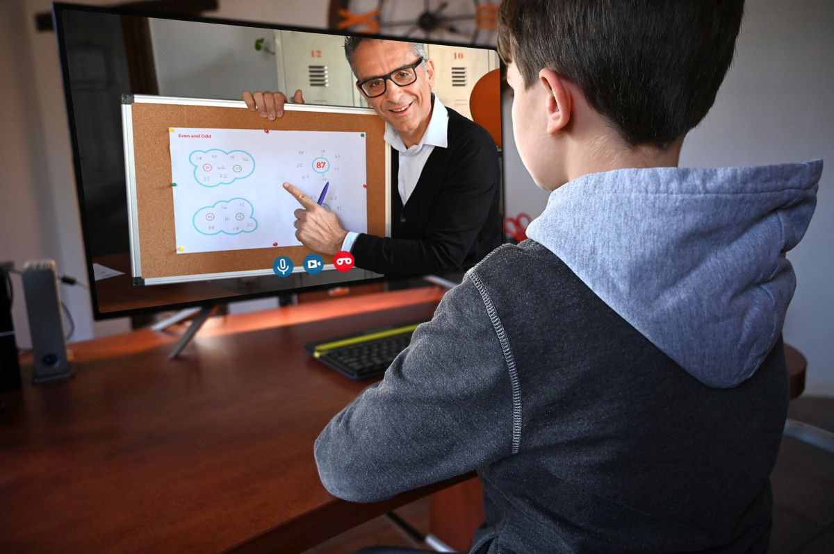 A child watches a teacher instruct through a computer screen