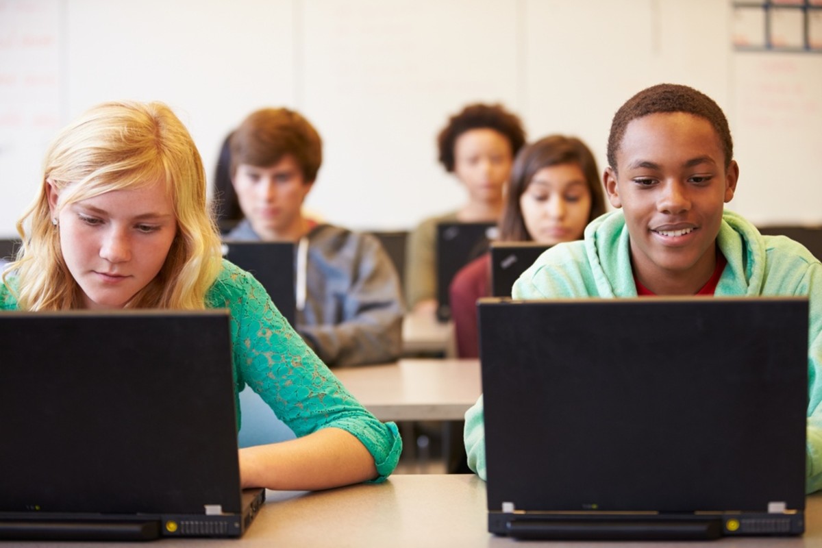 A group of students look at their laptop screens