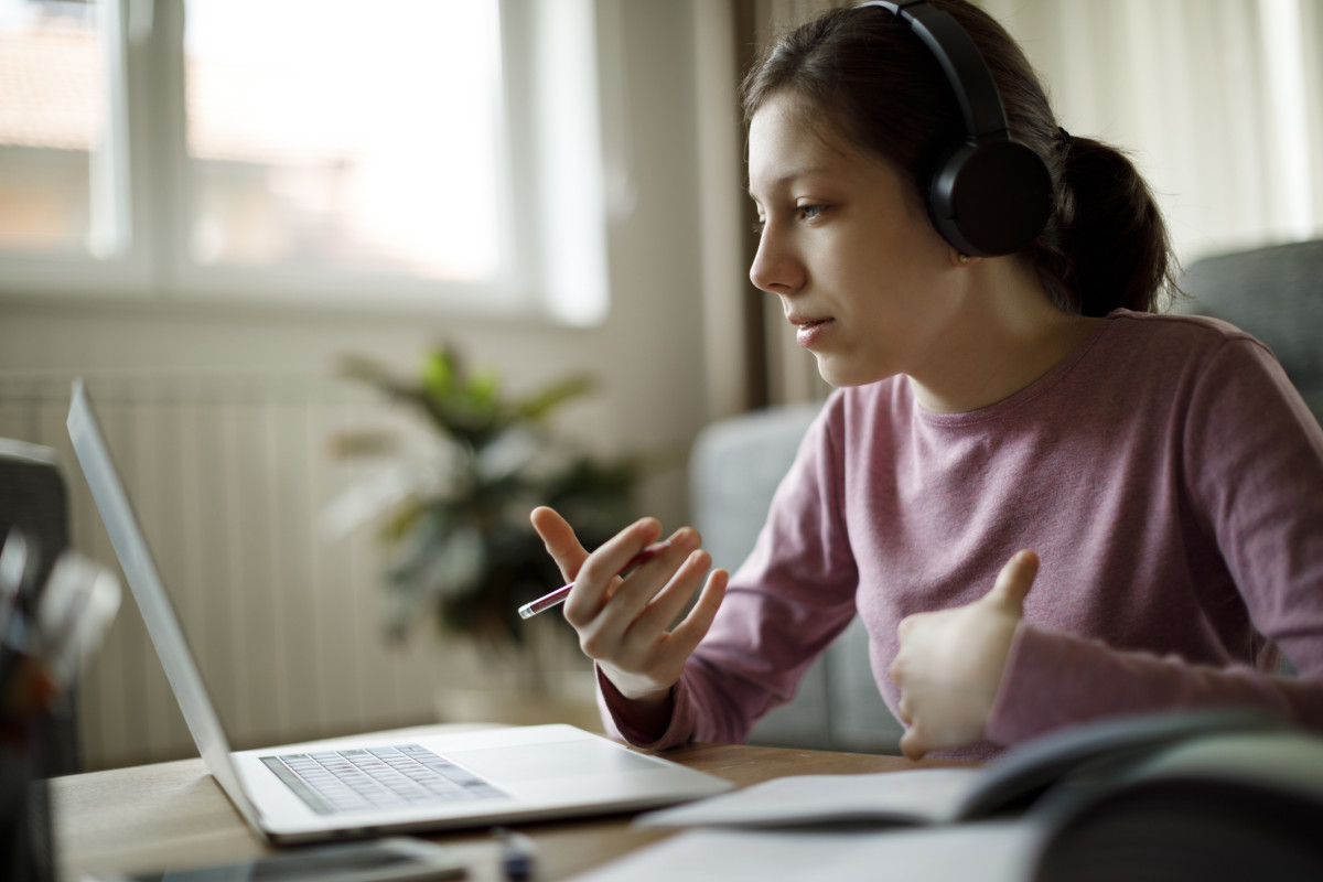 A student with headphones looks at her laptop screen