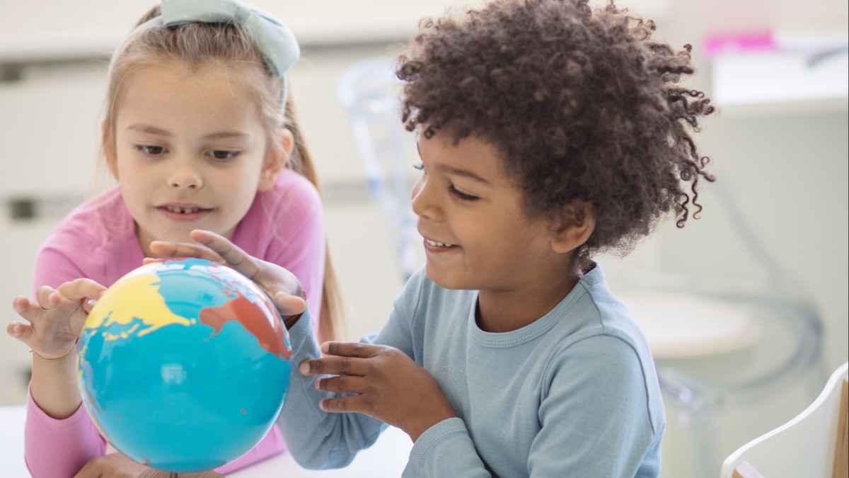 Two children touch a globe