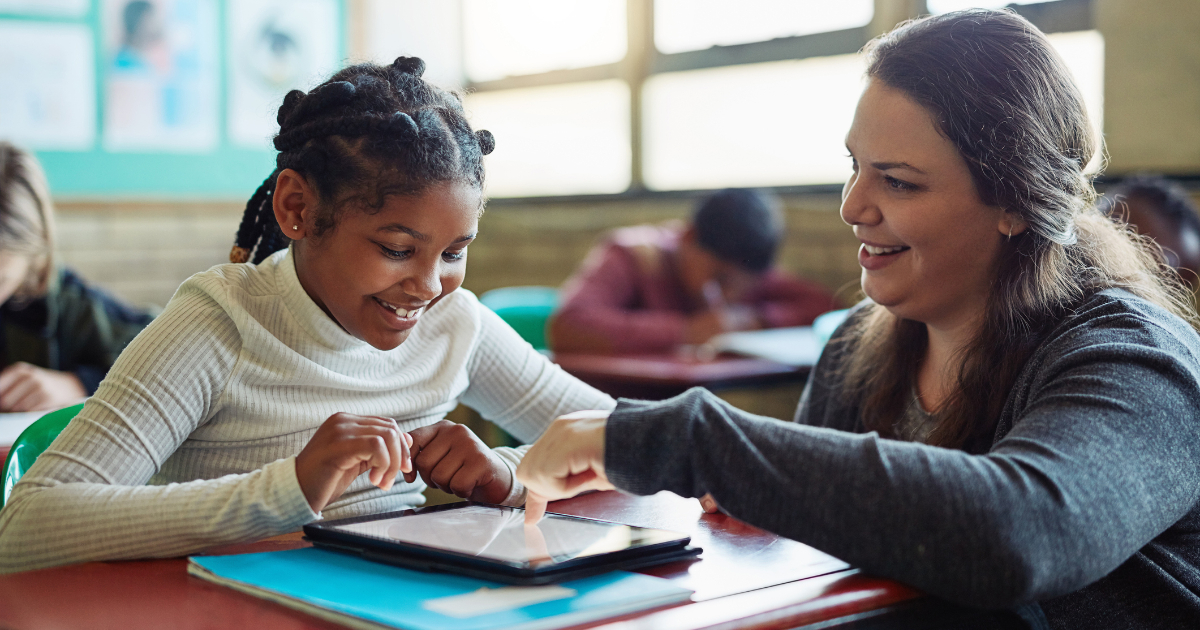 A teacher works with a student on a tablet