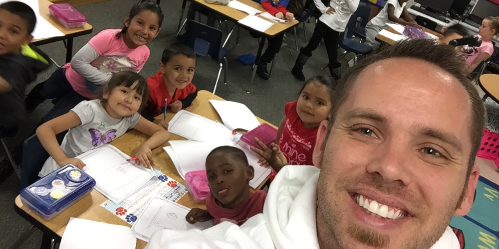 A man takes a selfie with a group of students