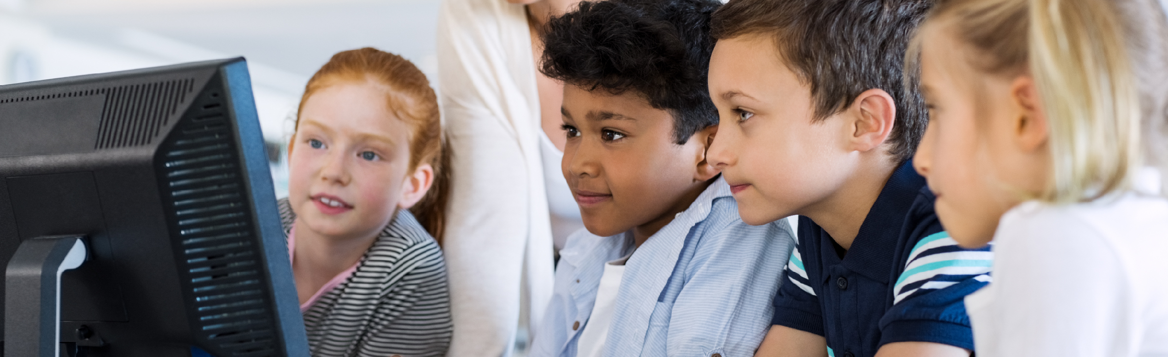 A photo of young students looking at a computer screen