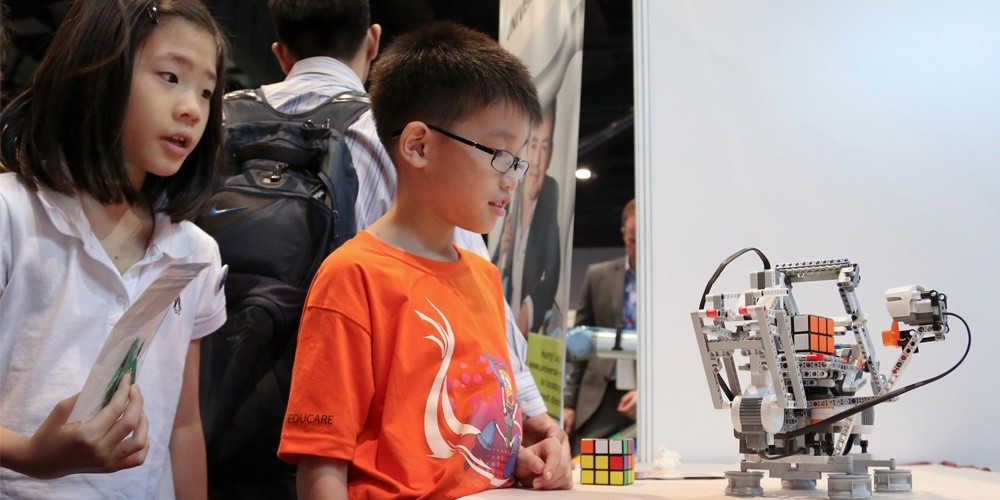 Two students stand by a robot