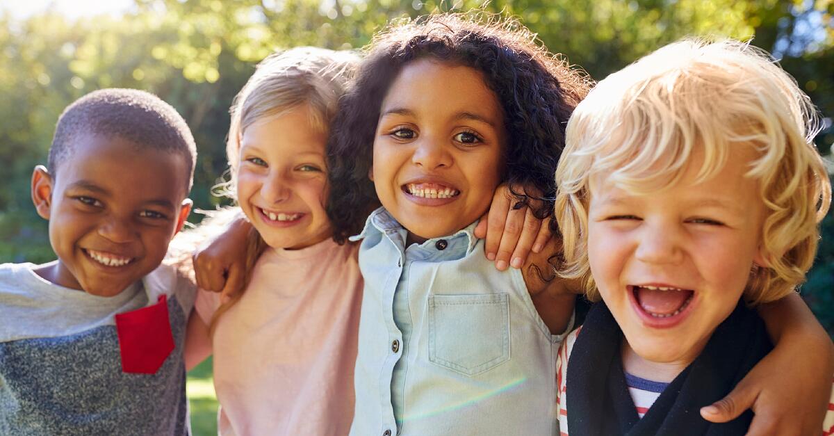 Four young children put their arms around eachother's shoulders